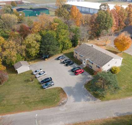 arial view of a home with a parking lot and trees in the background