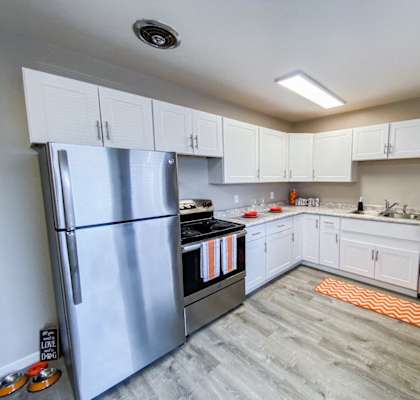 an empty kitchen with stainless steel appliances and white cabinets