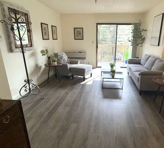 A living room with a grey couch, a coffee table, and a baby crib.