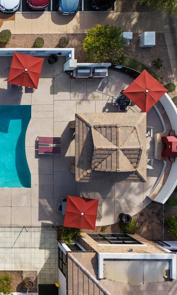 An aerial view of a pool surrounded by red umbrellas and chairs.
