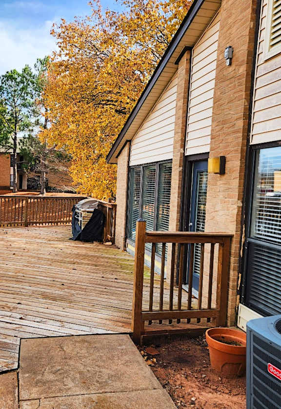 A deck with a railing and a tree in the background.