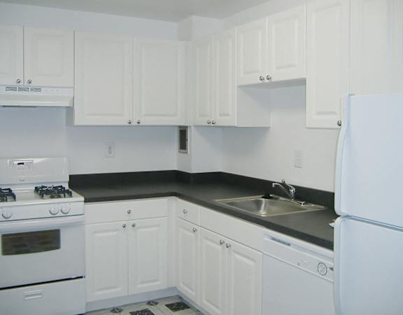 A white kitchen with a black countertop and white appliances.