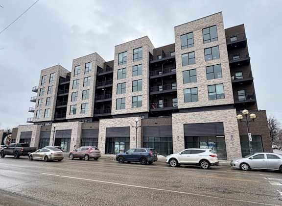 A large apartment building with cars parked in front.