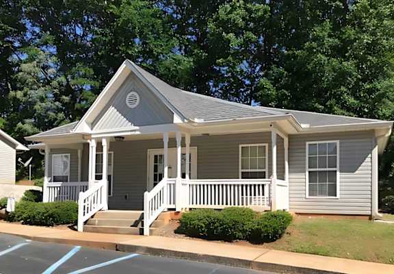 A small house with a porch and a front yard.