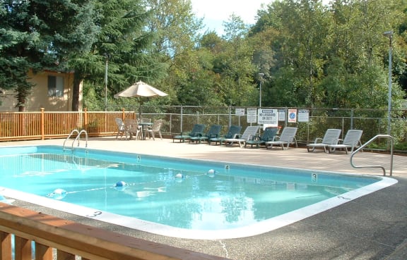 a resort style pool with chairs and an umbrella