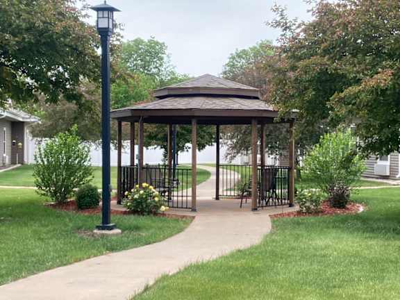 A gazebo is surrounded by a metal fence and a walkway.