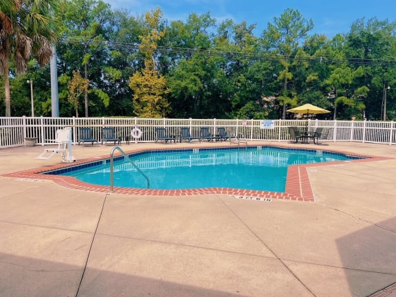a pool with a fence and chairs around it