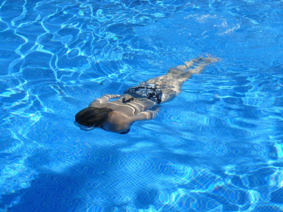 Person swimming underwater in pool at Mirabella Apartments, CA, 92203