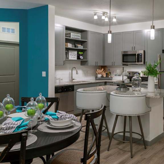 an open concept living room and dining area with a white dining table and rattan chairs at The Addison on Long Bayou Apartments, Seminole, Florida