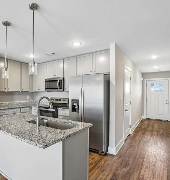 A kitchen with a granite counter top and stainless steel appliances.