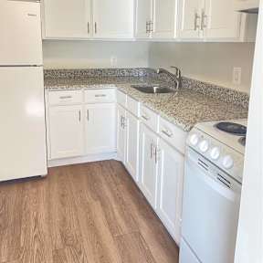 a kitchen with white cabinets and a wood floor