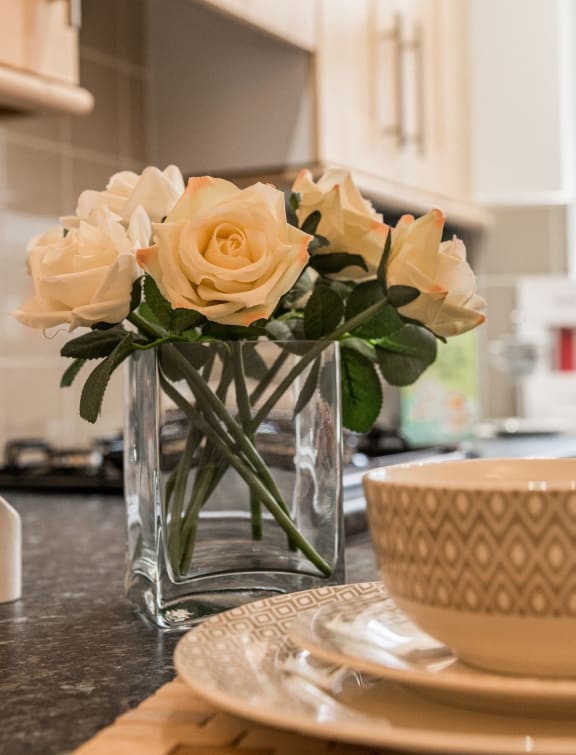 a vase filled with white roses on a kitchen counter