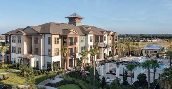 Aerial view of Alta East Shore, showing apartment complex, pool, and clubhouse with lush greenery