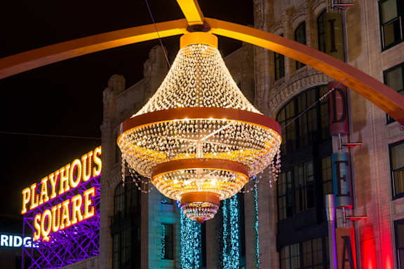 A large chandelier with lights hanging from it is in front of a Playhouse Square sign.