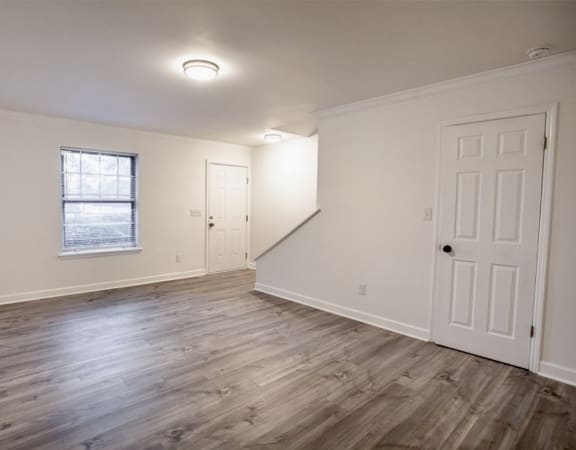 an empty living room with white walls and a window