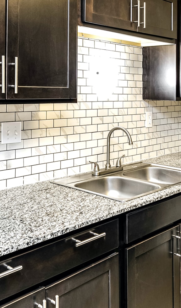 a kitchen with black cabinets and a granite counter top