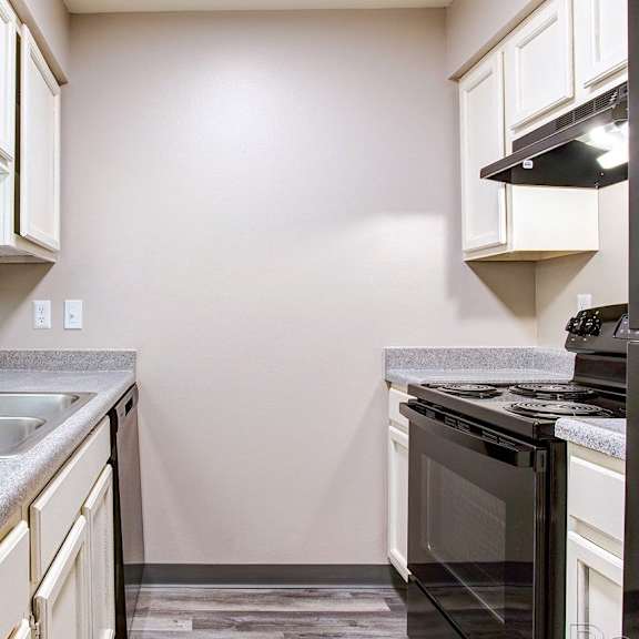 A kitchen with a black oven and a grey countertop.