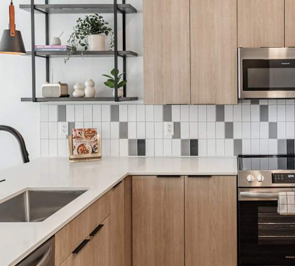A modern kitchen with wooden cabinets and a black and white checkered backsplash.