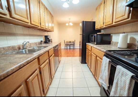 A kitchen with wooden cabinets and a black refrigerator.