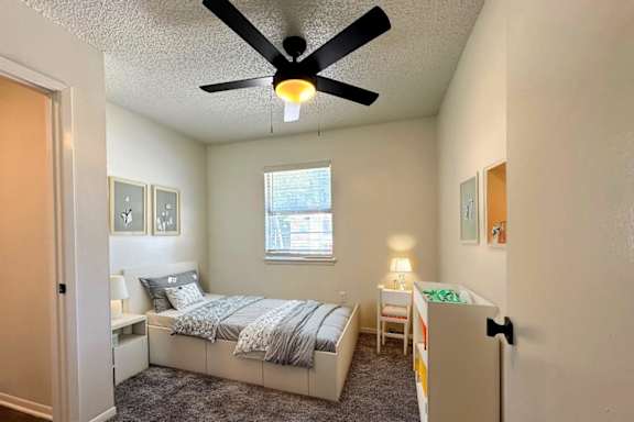 A bedroom with a bed, a nightstand, and a window.