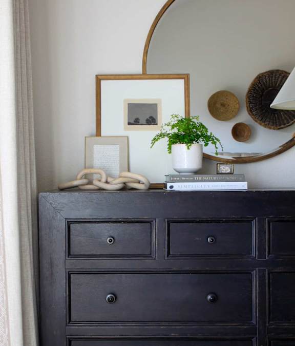 A black dresser with a mirror above it.