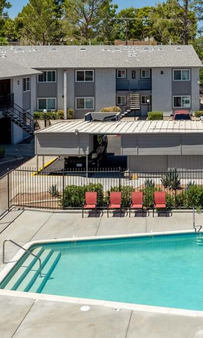 A pool surrounded by a black fence and chairs.