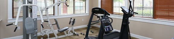 A home gym with a treadmill, a stationary bike, and a weight bench.