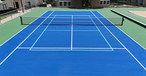 A blue tennis court with white lines and a net.