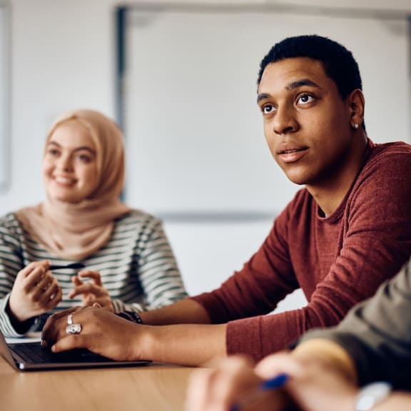 a group of people sitting around a table with a laptop