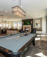 a pool table in a clubhouse with a bar and a fireplace