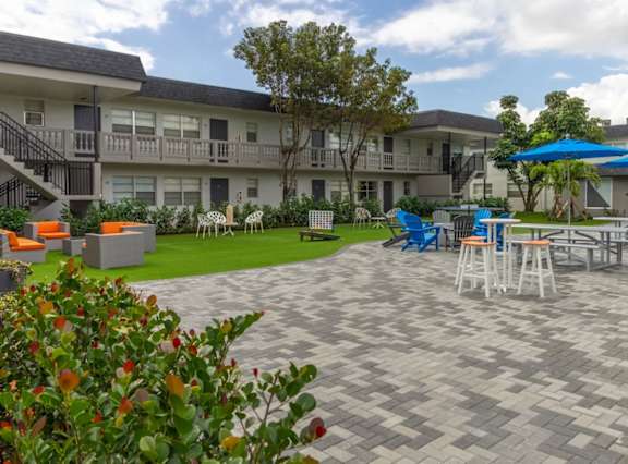 A patio area with a table and chairs and a blue umbrella.