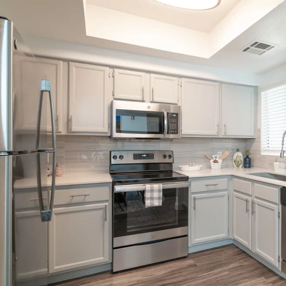 a kitchen with white cabinets and stainless steel appliances