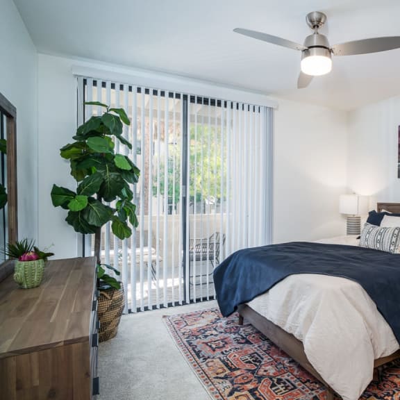 a bedroom with a large window and a ceiling fan