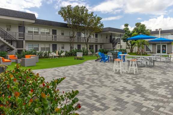 A patio area with a table and chairs and a blue umbrella.