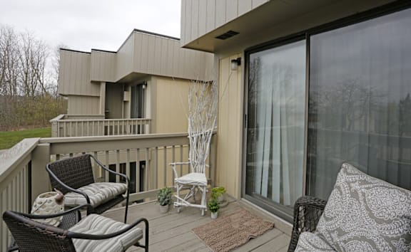 A balcony with a couch, chairs and a table.