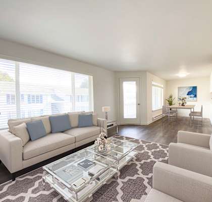 Spacious living room with wood-like flooring, an oversized window with nature views, and a door to a private balcony.at The Trail, Snohomish