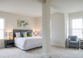 a bedroom with a bed and a chair and a window