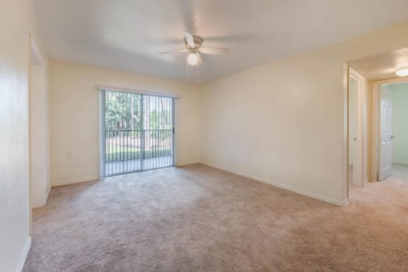 Carpeted Living Room with Ceiling Fan and  Sliding Glass Door with Vertical Blinds