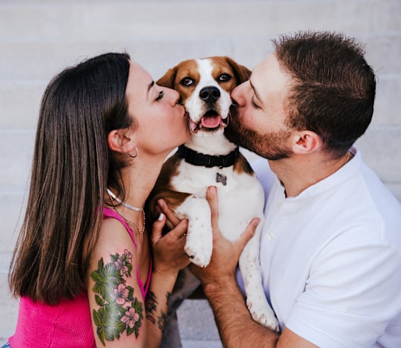 a man and a woman kissing a dog
