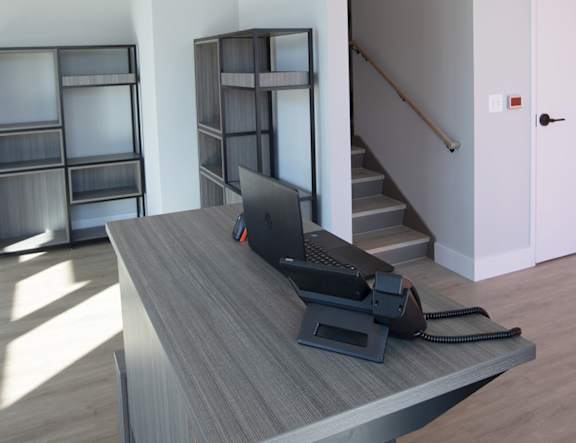 A black laptop is on a desk with a black telephone next to it at The Pearl, Fort Wayne, 46802