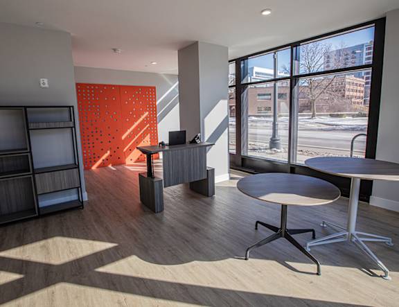 A modern office space with a wooden floor and a large window overlooking the street at The Pearl, Fort Wayne, 46802