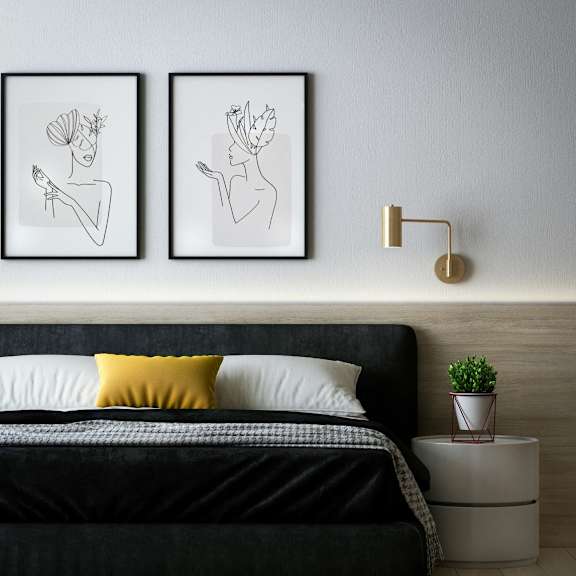 A bedroom with a black bed and two framed artworks on the wall.