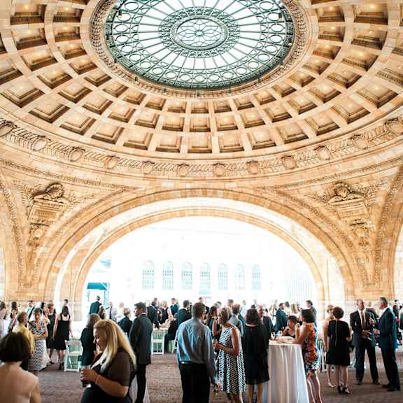 A large group of people are gathered in a grand hall with a beautiful glass dome ceiling. at The Pennsylvanian Apartments, Pittsburgh, Pennsylvania
