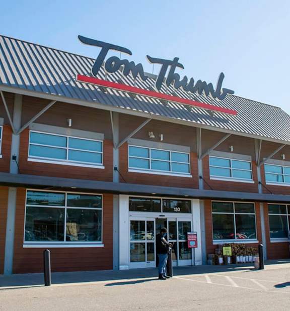 A Tom Thumb store with a person standing in front.