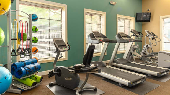 a gym with treadmills and other exercise equipment at the enclave at university crossings