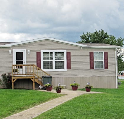 A house with a grey siding and red window frames.