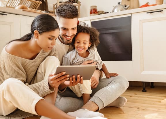 Family looking at tablet in kitchen Eagles Pointe in Pompano Beach Florida at Eagle Pointe, Pompano Beach, FL