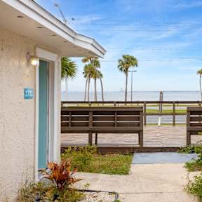 the view of the ocean from the porch of a house with a deck and benches
