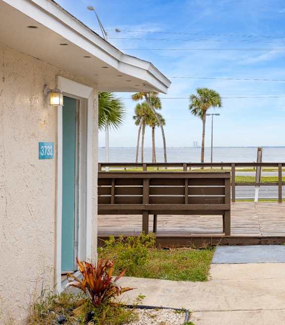 the view of the ocean from the porch of a house with a deck and benches