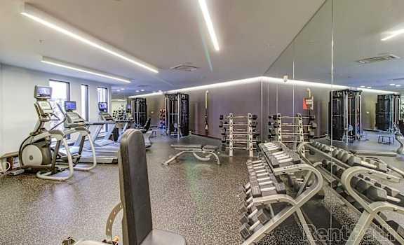 a gym with cardio equipment and mirrors in a condominium